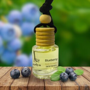 Difusor Colgante Blueberry para Auto Jazlyn Perfumería , sobre fondo vibrante con arándanos frescos, ideal para una fragancia frutal, dulce y energizante en el auto .